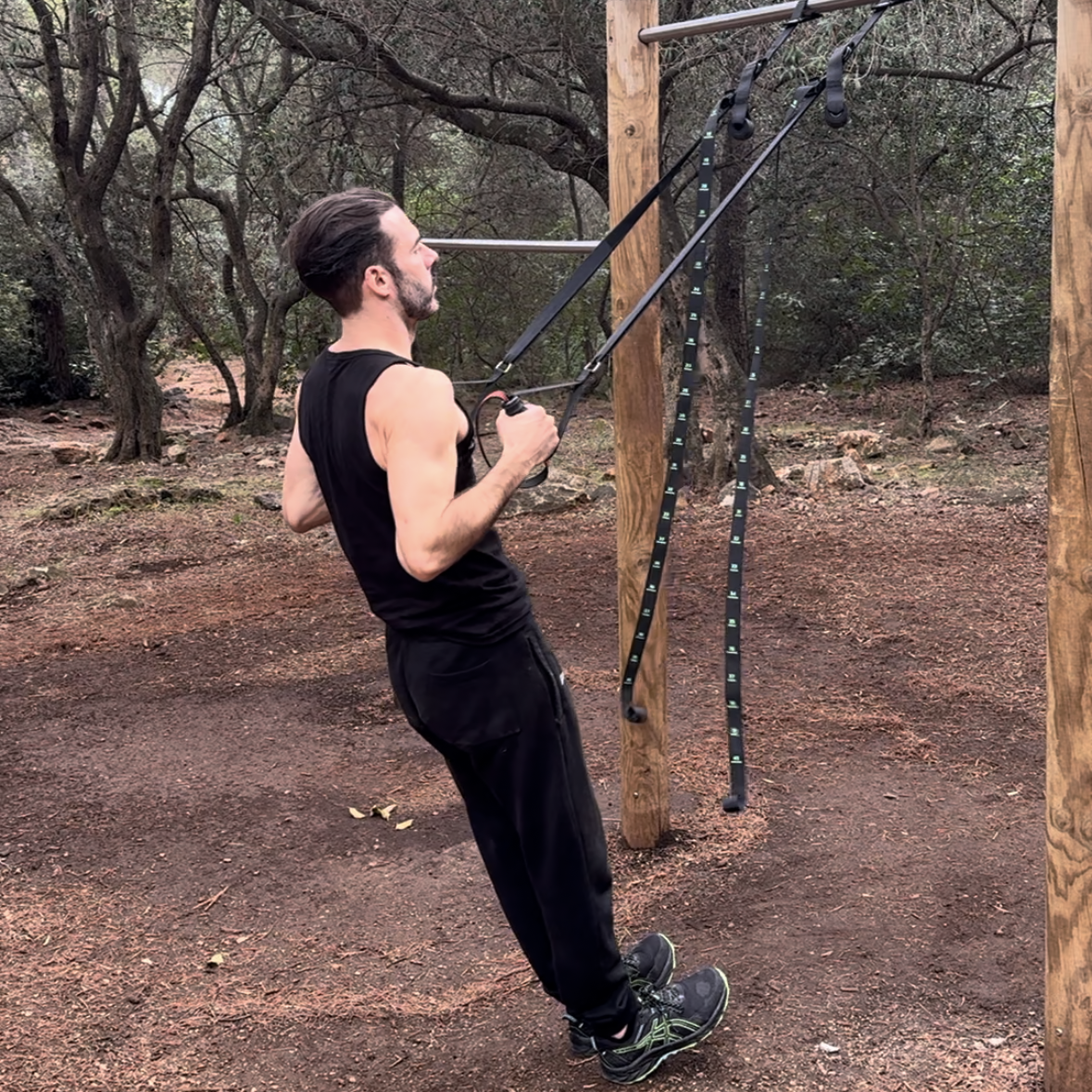 Un homme réalisant un exercice de traction avec des sangles de suspension GymKross dans une forêt, démontrant l'efficacité des sangles pour améliorer la force, l'équilibre et la stabilité lors d'un entraînement en plein air.
