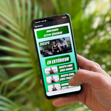 Main tenant un smartphone affichant l&#39;application GymKross avec une sélection de tutoriels d&#39;entraînement pour les biceps, comprenant des options pour s&#39;entraîner en extérieur comme &#39;Biceps Curl avec barre&#39; et &#39;Biceps Curl avec poignées&#39;. L&#39;interface de l&#39;application sur fond de végétation évoque la facilité d&#39;accès à des séances d&#39;entraînement personnalisées n&#39;importe où, n&#39;importe quand.