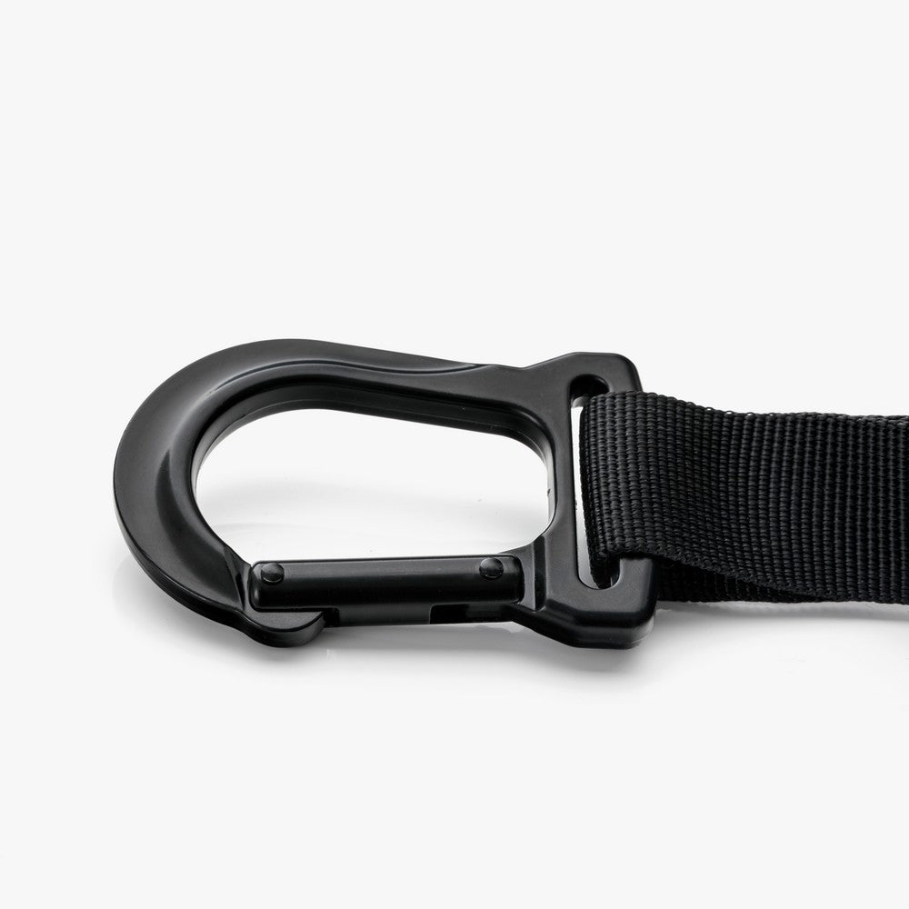 "Mousqueton robuste en métal noir fixé à une sangle GymKross, conçu pour offrir une sécurité maximale et une résistance élevée lors des exercices de suspension et d'entraînement intense."