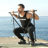 "Homme en tenue GymKross effectuant un squat en plein air avec une barre d'entraînement, face à la mer. Environnement de fitness en bord de mer."