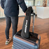 Voyageur à l'aéroport avec le kit de fitness Gymkross attaché à sa valise, démontrant la facilité de maintenir une routine d'entraînement pendant les déplacements.